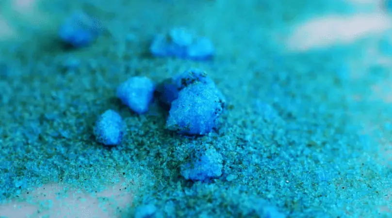 A close up of blue powder on a table, emphasizing COPPER SULFATE or CHELATED COPPER for pond care.