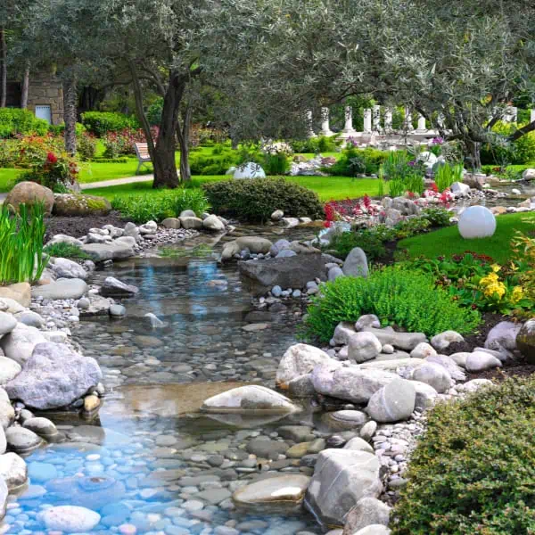 A serene stream in a garden, integrated with meticulous lake management services.