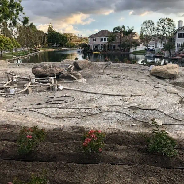 A new house is being built with a large rock in the middle of the yard that requires management.