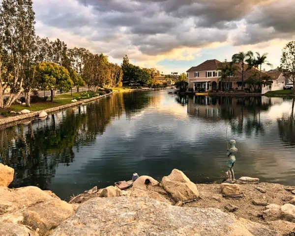 A serene lake surrounded by charming houses and majestic rocks.